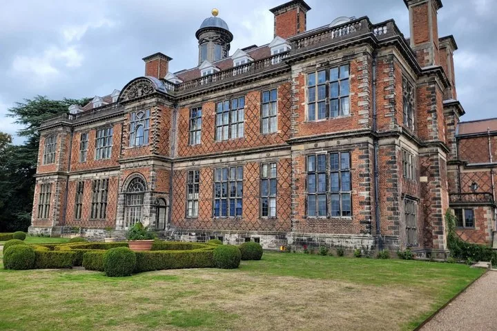 A large, historic brick mansion with patterned brickwork and formal gardens.